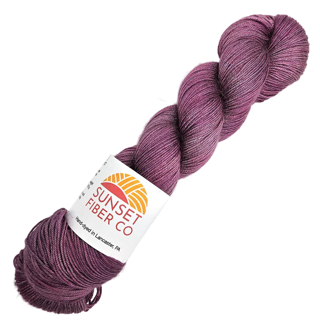 A skein of purple yarn labeled 'Sunset Fiber Co' on a white background.